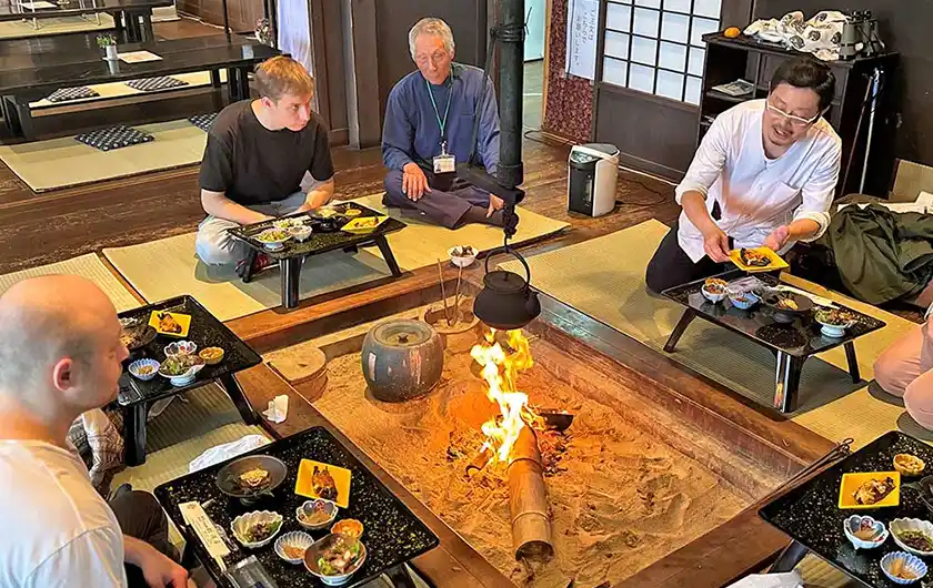 囲炉裏を囲んで福島潟の地元料理を楽しむ人々