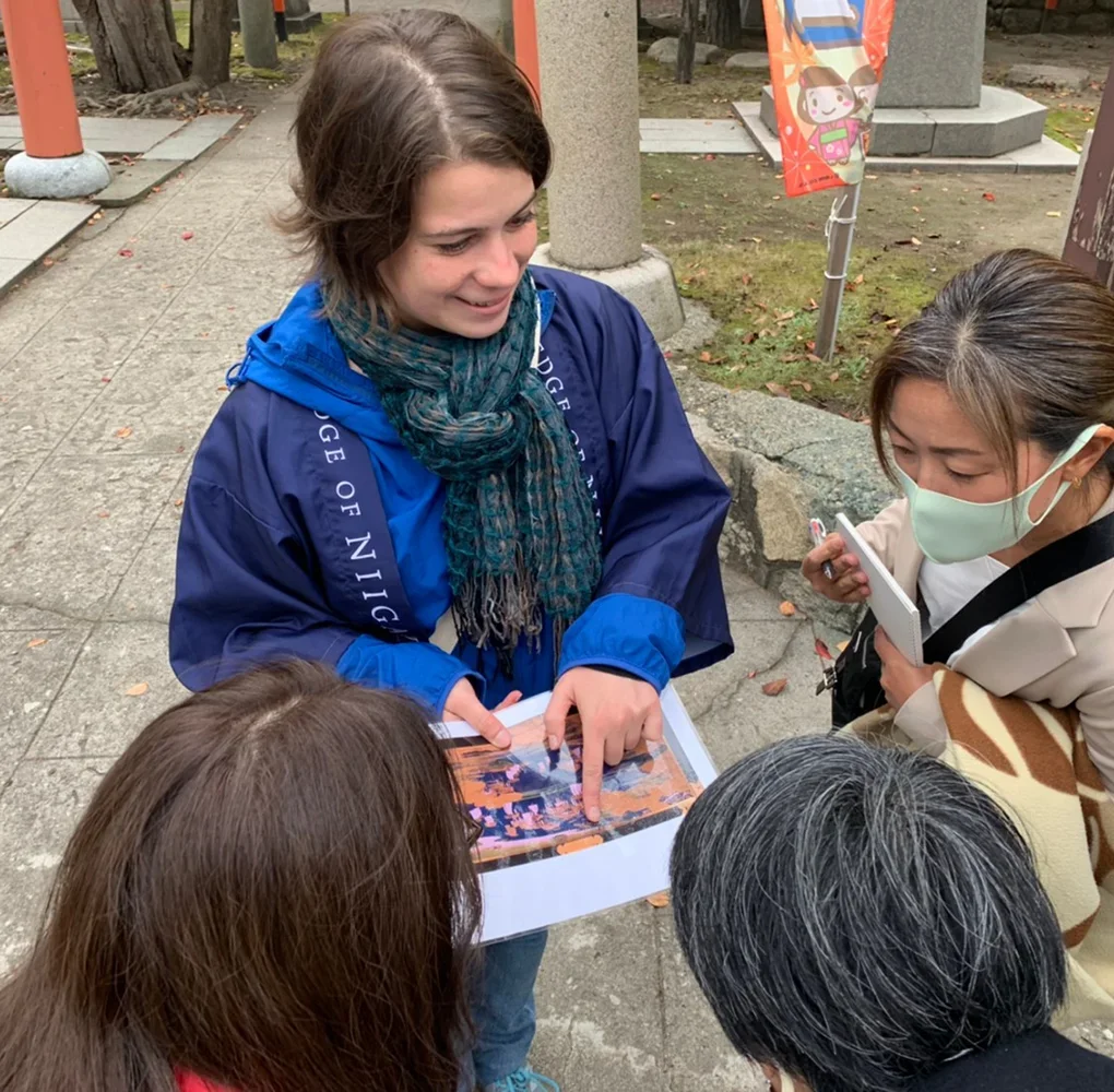 Foreign woman guiding a group of people with a map at a Japanese shrine during a cultural tour