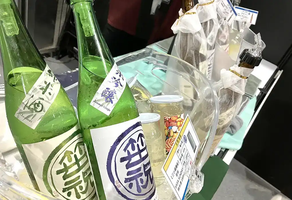 Close-up of chilled Japanese sake bottles displayed at a food and beverage exhibition